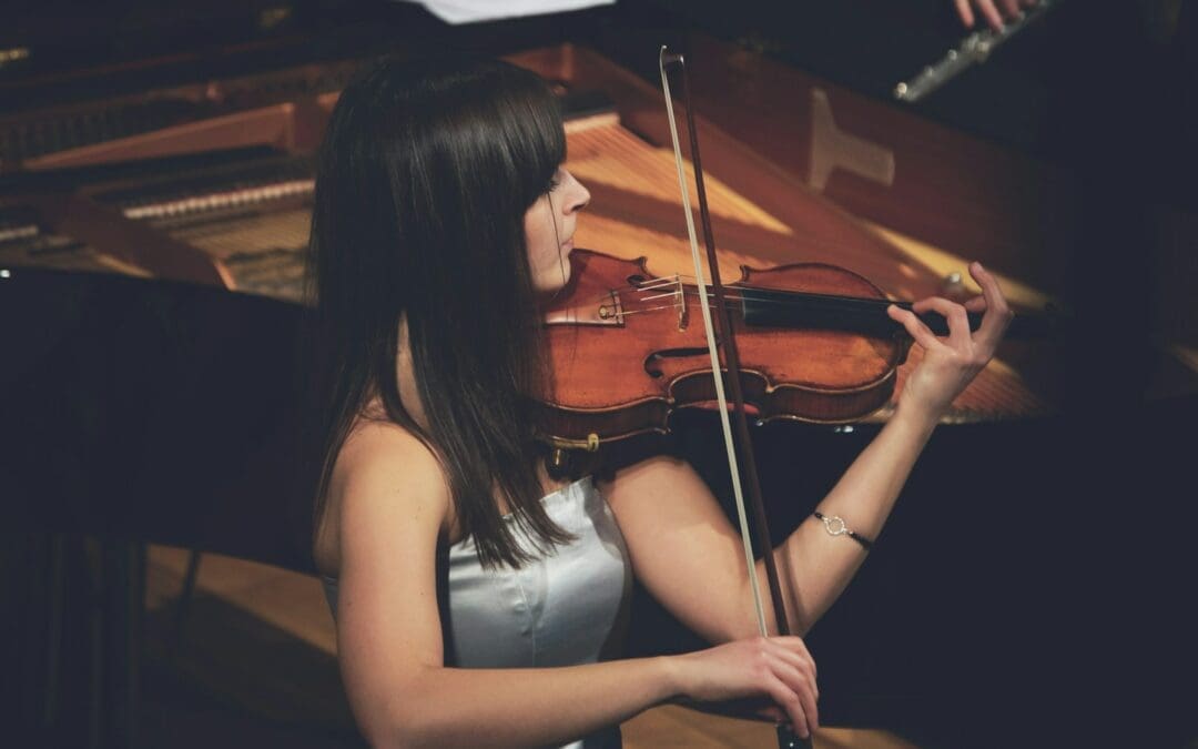 woman playing violin beside grand piano