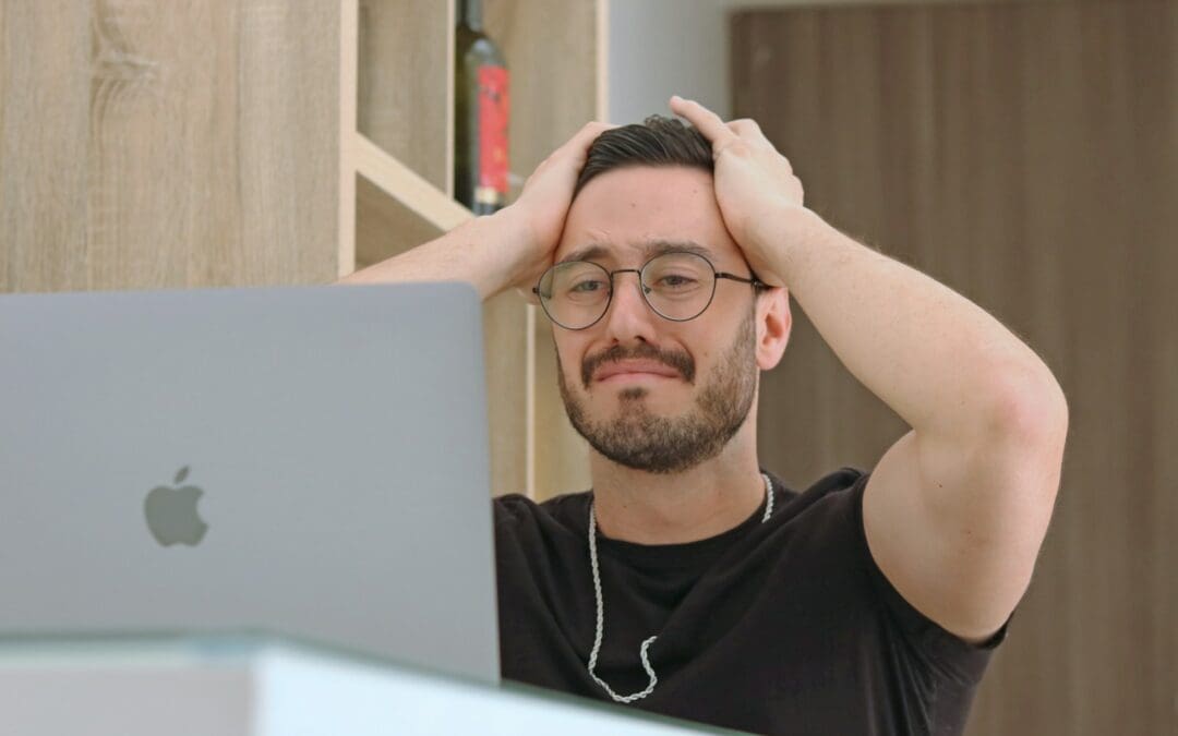 a man with glasses is looking at a laptop